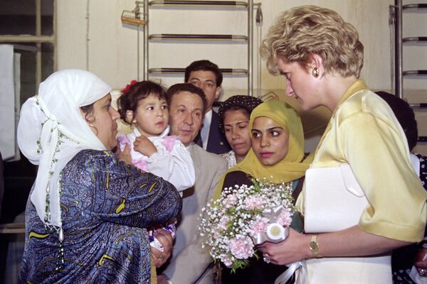 Принцесса Диана Уэльская говорит с женщиной, держащей ребенка, в Обществе за благополучие матерей и детей в Каире 12 мая 1992 года, во второй день ее пятидневного визита в Египет - Sputnik Латвия