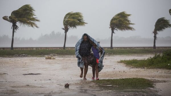 Женщина с ребенком защищаются одеялом от дождя и ветра в Кайбариене, Куба - Sputnik Латвия