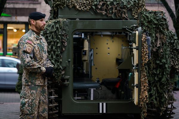 Латвийский военный у латвийского бронетранспортера CVRT Латвийский военный у латвийского бронетранспортера CVRT - Sputnik Латвия