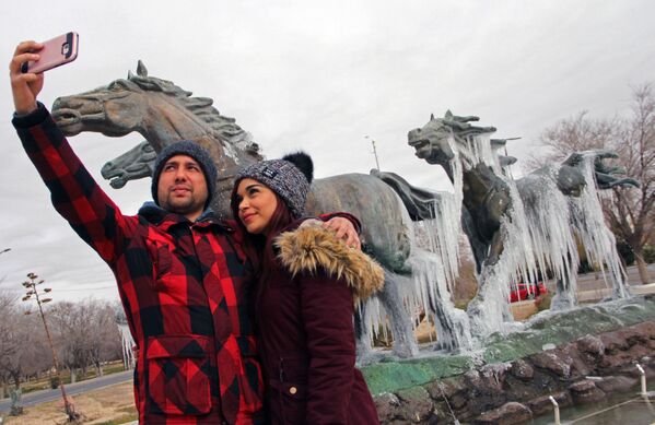Пара делает селфи перед памятником, покрытым льдом, после похолодания в Сьюдад-Хуаресе, Мексика - Sputnik Латвия