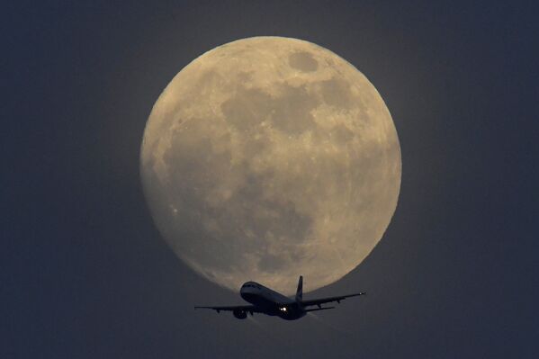 Самолет на фоне полной луны в небе над Лондоном, Великобритания - Sputnik Латвия