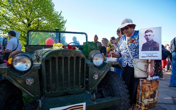 Ретроавтомобиль организации Ordenis 9 мая в Парке Победы, гостья праздника угощается кашей с полевой кухни - Sputnik Латвия
