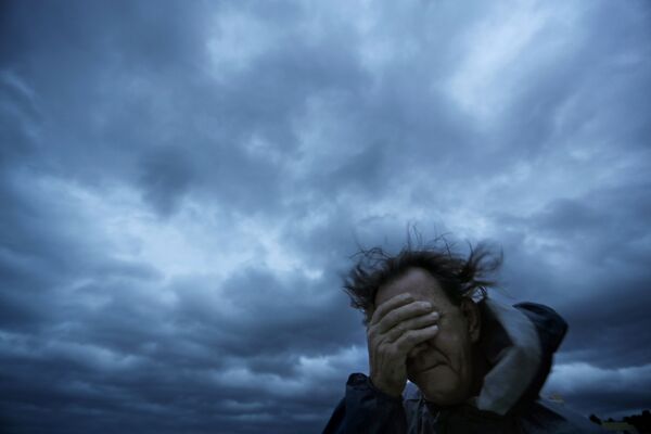 Мужчина закрывает лицо от ветра и песка во время урагана Флоренс в Мертл-Бич, США - Sputnik Латвия