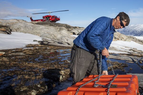 Сотрудник службы безопасности собирает оборудование для работы в научном лагере на леднике Хелхейм в Гренландии - Sputnik Латвия
